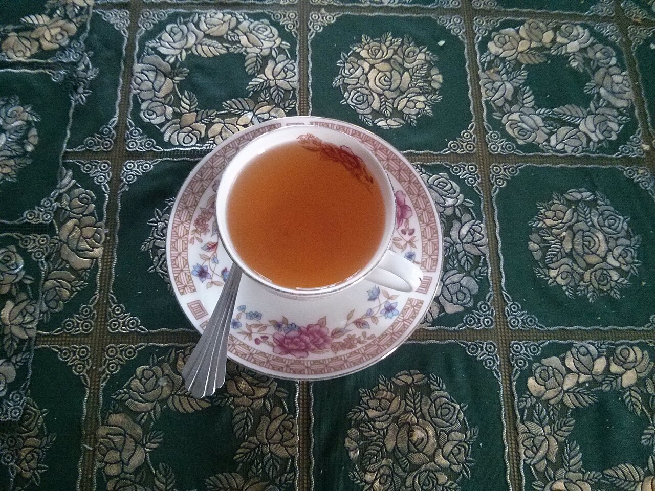 A cup of Kashmiri kahwa on a patterned tablecloth